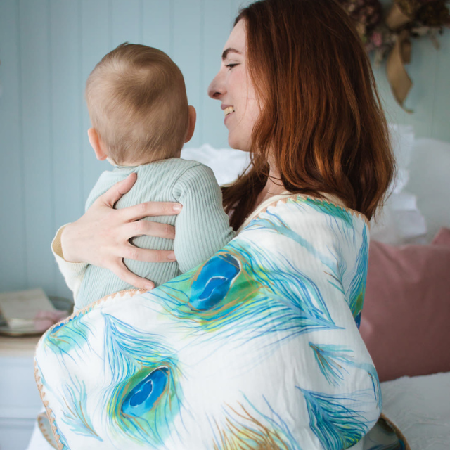 Mum and bub wrapped in waffle blanket with peacock design.