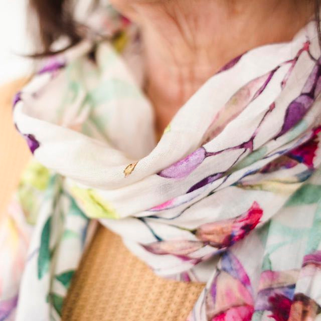 Close up of lady wearing scarf which is white and has colourful Australia flower artwork printed on