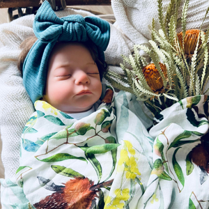 Baby wrapped in swaddle with wattle and banksia design