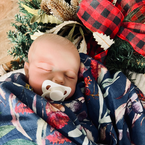 Newborn baby wrapped in baby swaddle with Christmas print